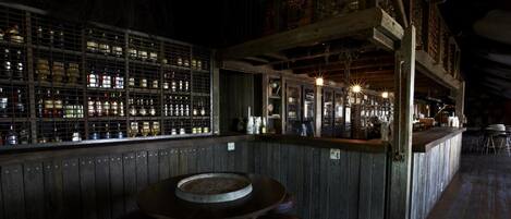 A bar area with wooden walls, a high ceiling, and a bar counter with stools.