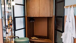 Un baño pequeño con dos lavamanos, un perchero para toallas y un armario de madera.