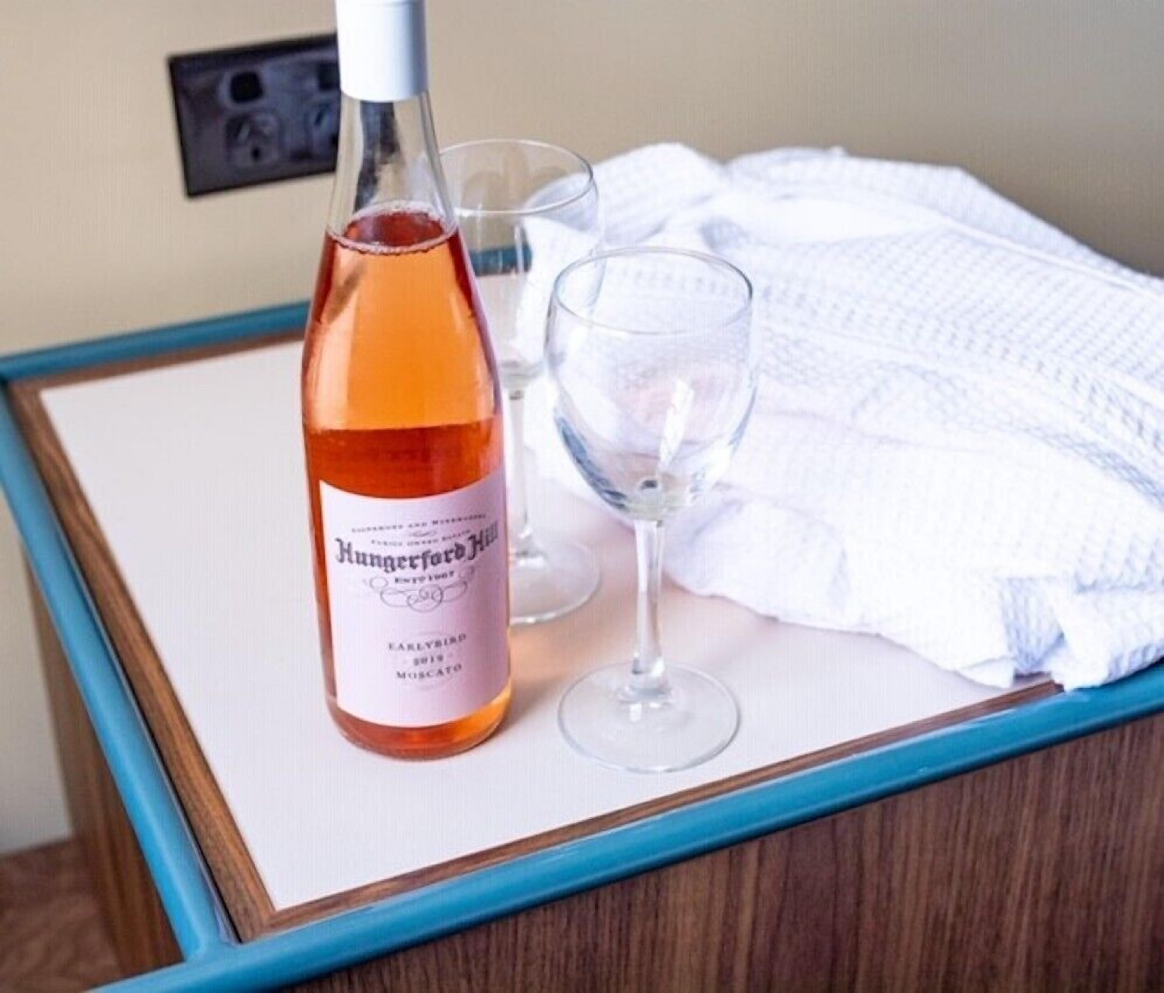 A bottle of wine and two glasses on a table with a white cloth and a blue frame.