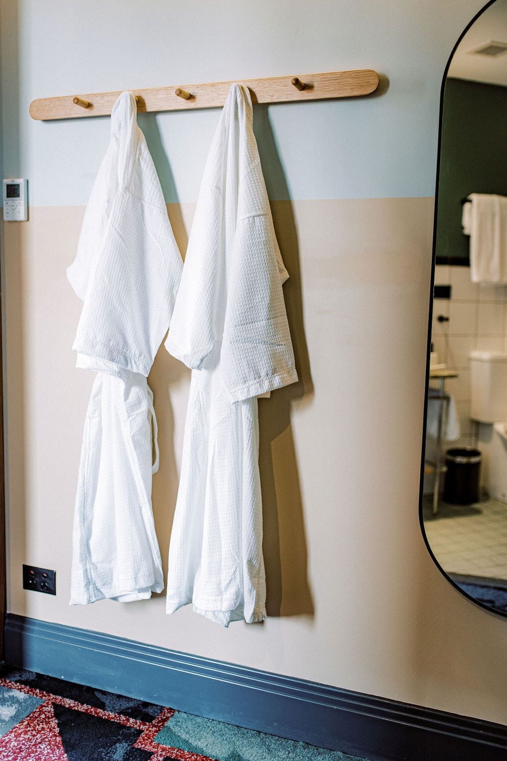 A bathroom with a wooden towel rack holding two white towels.