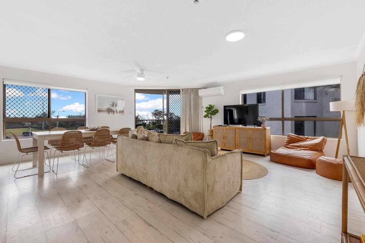 A modern living room with a sofa, dining table, chairs, and a TV.