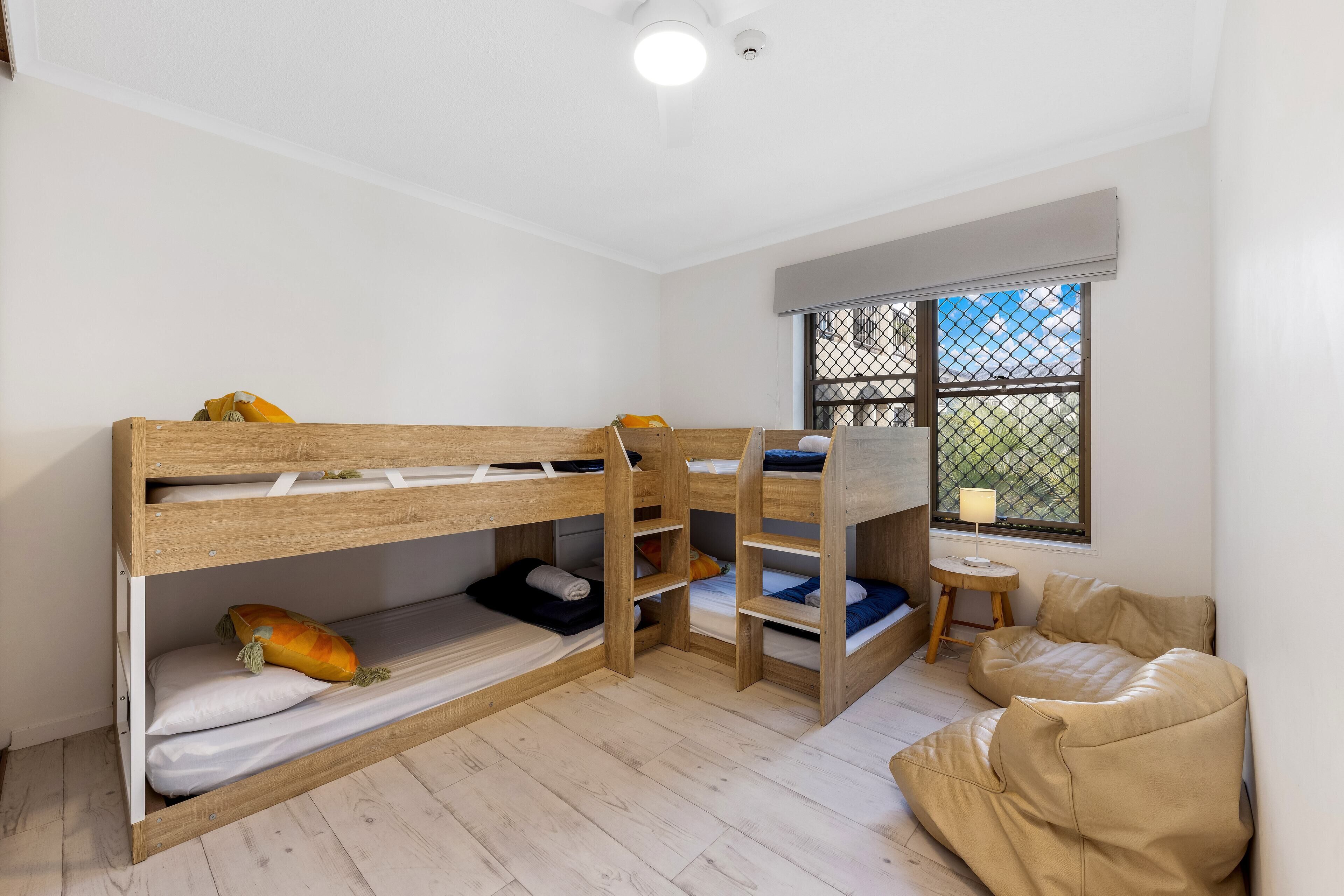 A room with bunk beds, a window with a view, and a small table with a lamp.