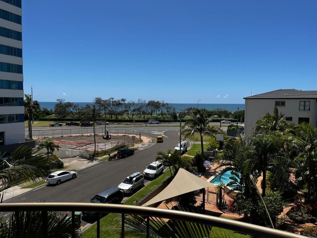 A view of a road with cars, a pool area, and a building in the background.