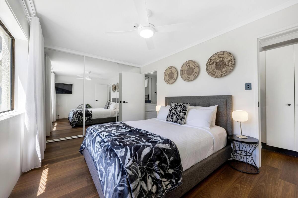 A modern bedroom with a large bed, a bedside table with a lamp, and decorative wall plates.