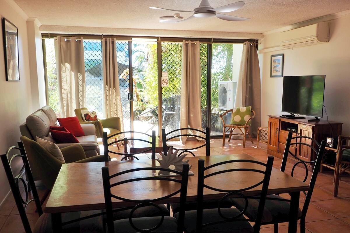 A dining area with a table and chairs, a sofa, and a television.