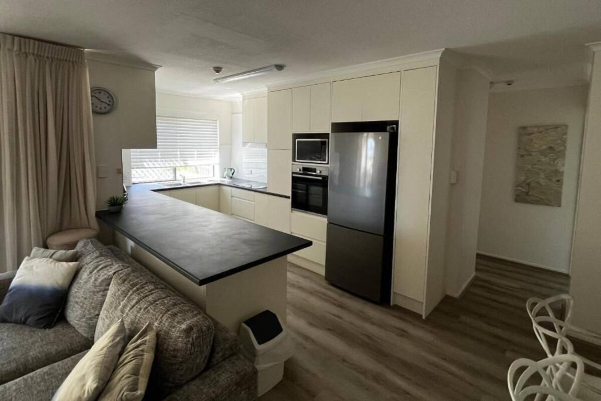 A modern kitchen with a central island, built-in appliances, and a dining area with a sofa and chairs.