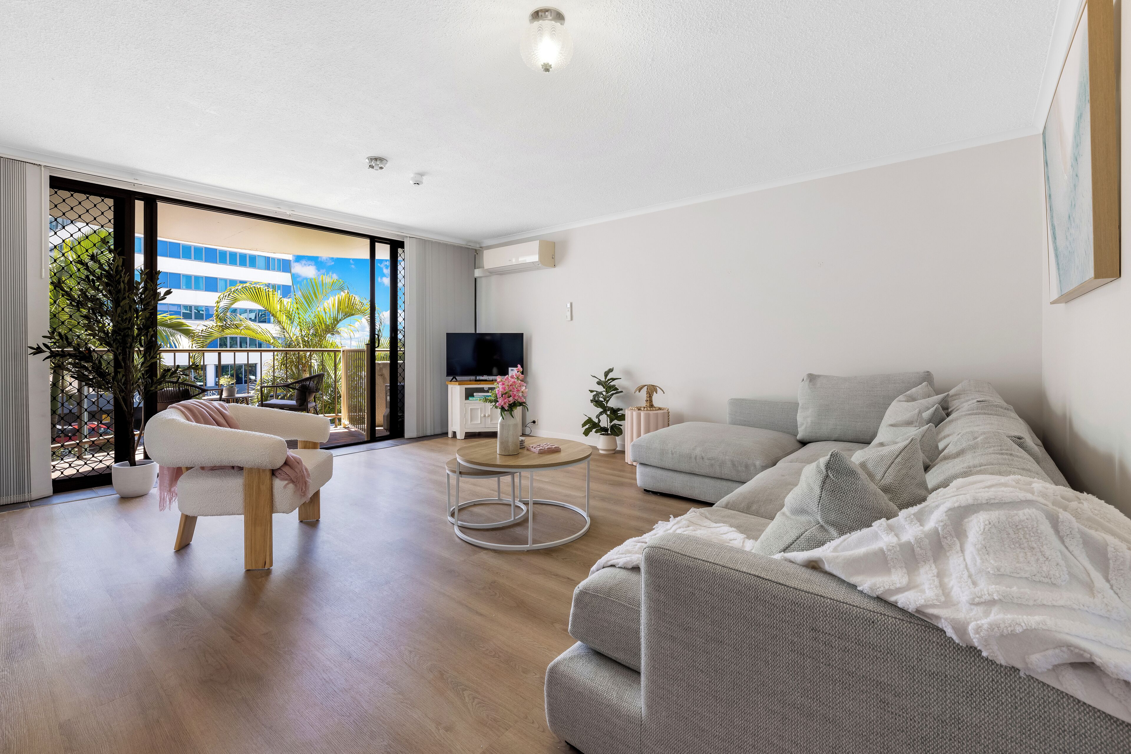 Un salon moderne avec un canapé gris, un fauteuil blanc et une table basse ronde.