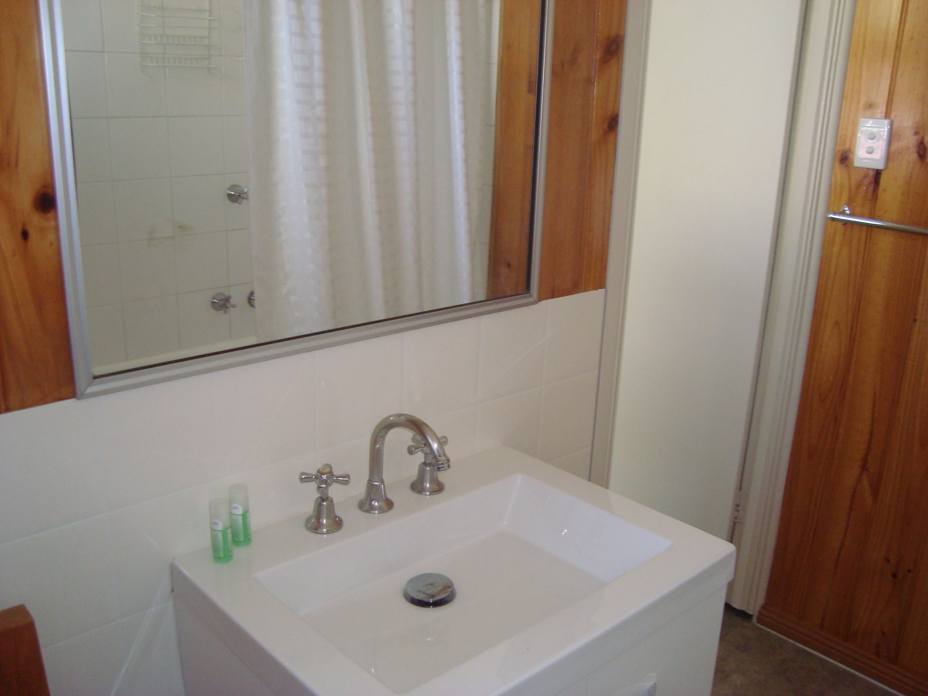 A bathroom with a white sink, two faucets, and a mirror above it.