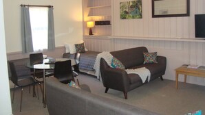 A living room with a sofa, chairs, a dining table, and a TV. - Elm Lodge (Bright)