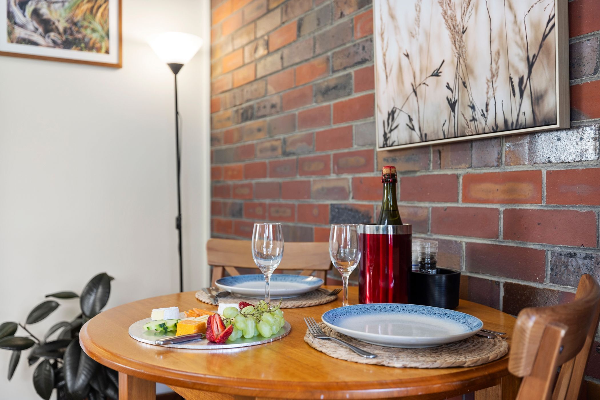 Una mesa de comedor con platos, cubiertos, una botella de vino y una copa.