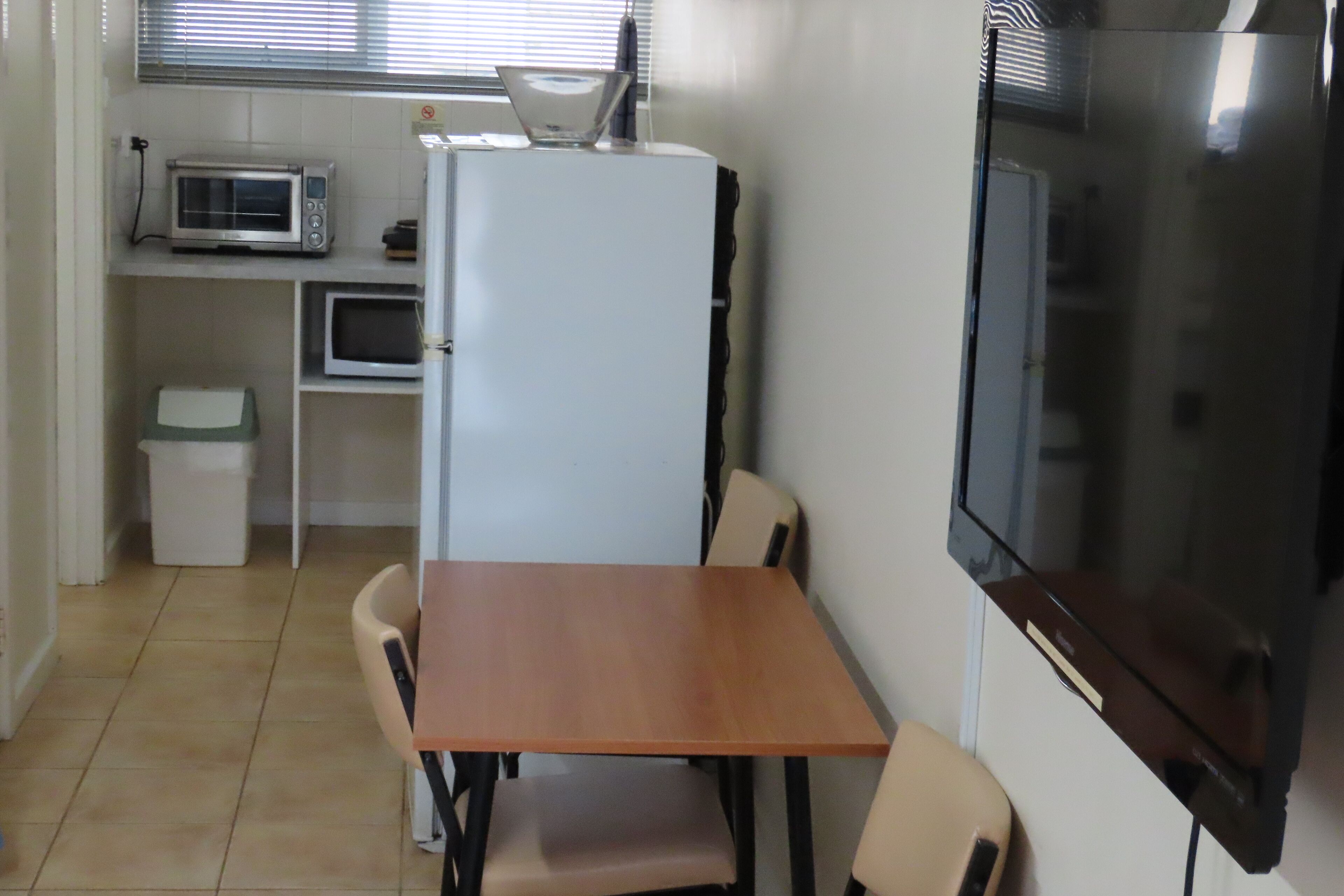 Uma cozinha compacta com micro-ondas, geladeira e TV de tela plana.