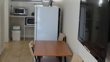 Uma cozinha compacta com micro-ondas, geladeira e TV de tela plana.