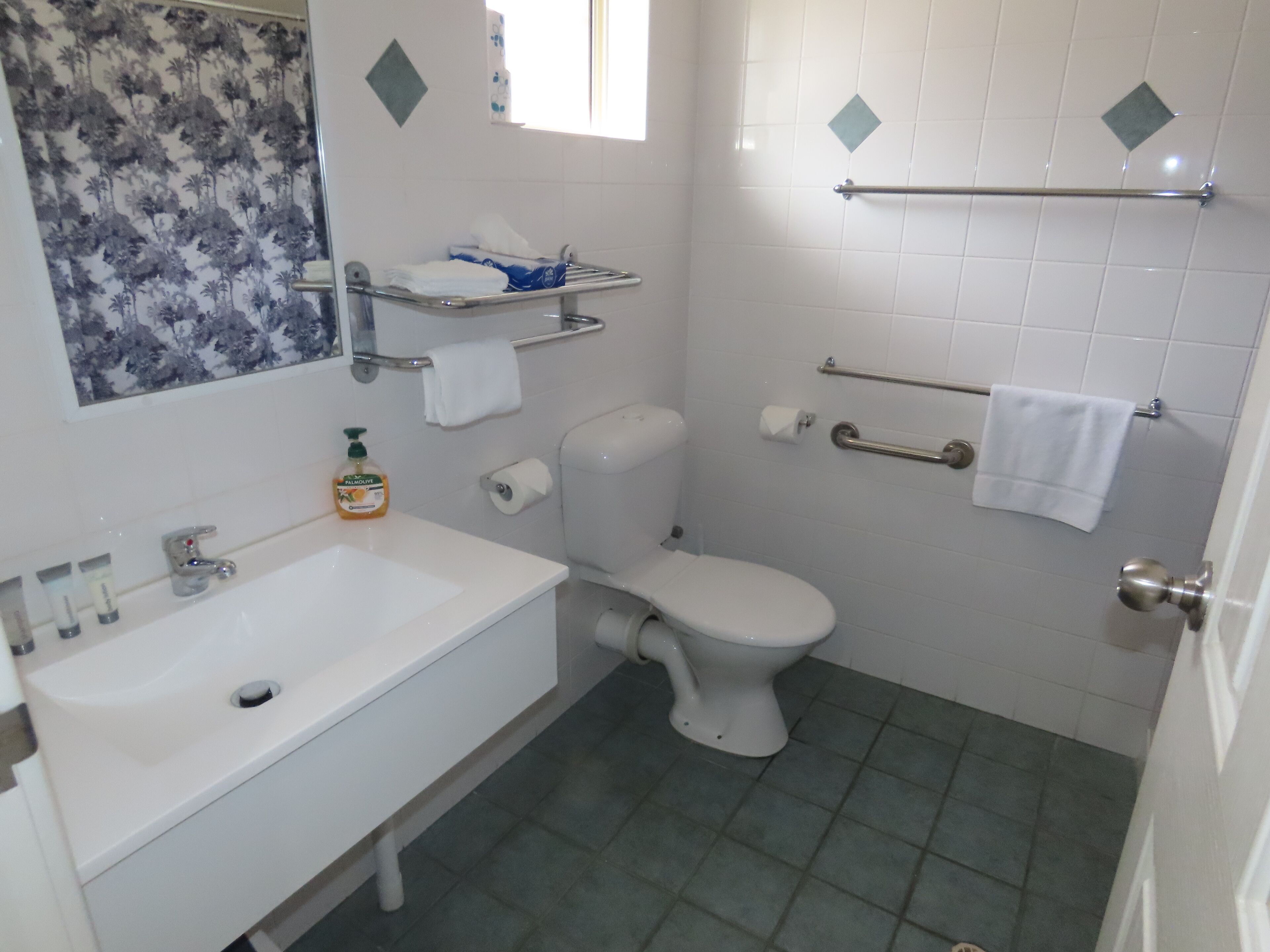 A bathroom with a white sink, toilet, and a shower area.
