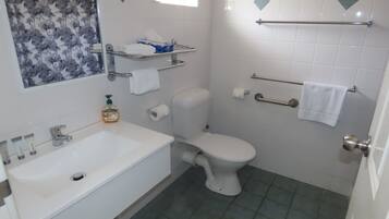 A bathroom with a white sink, toilet, and a shower area.