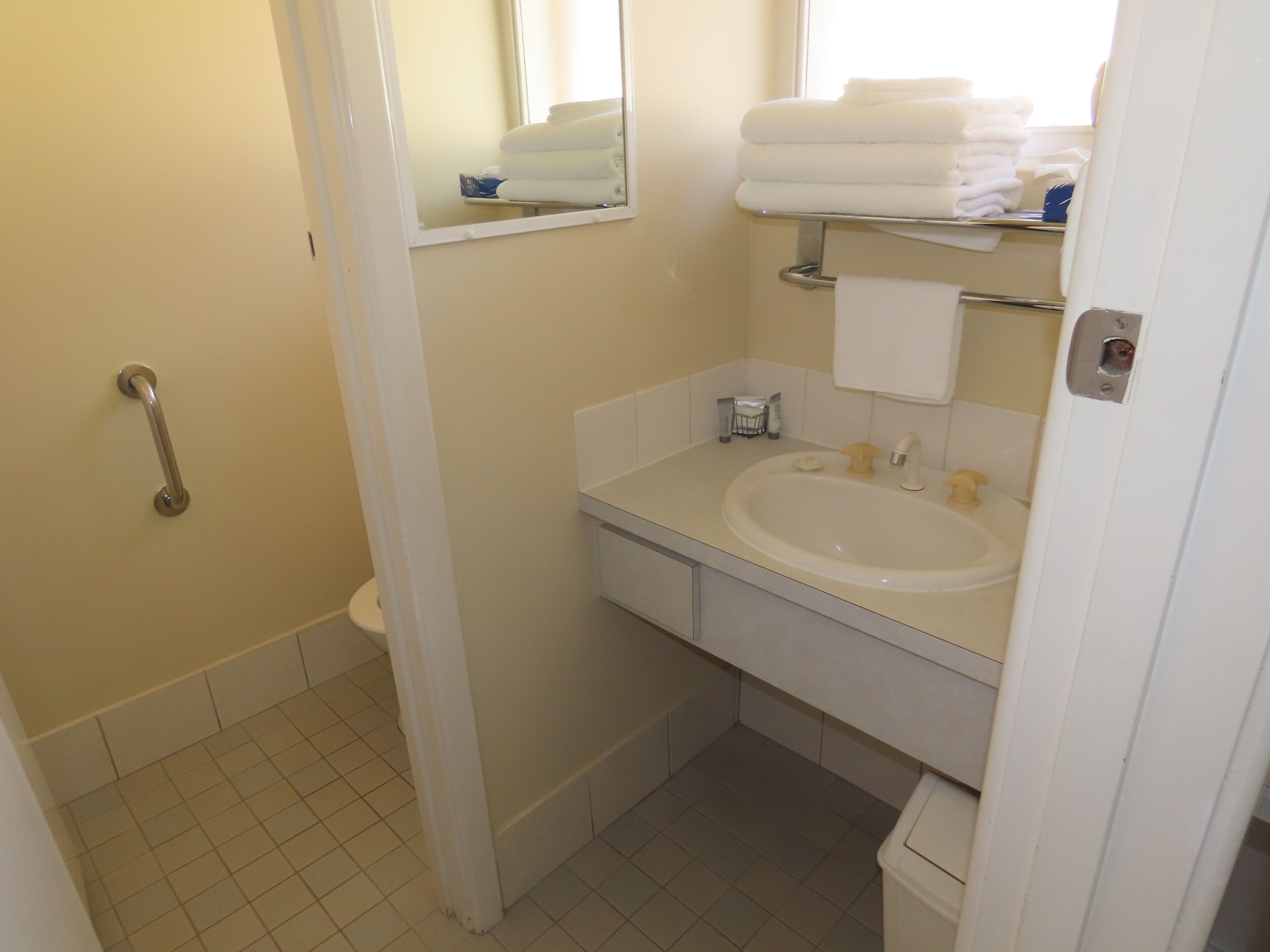 Baño con lavamanos blanco, espejo y barandilla.