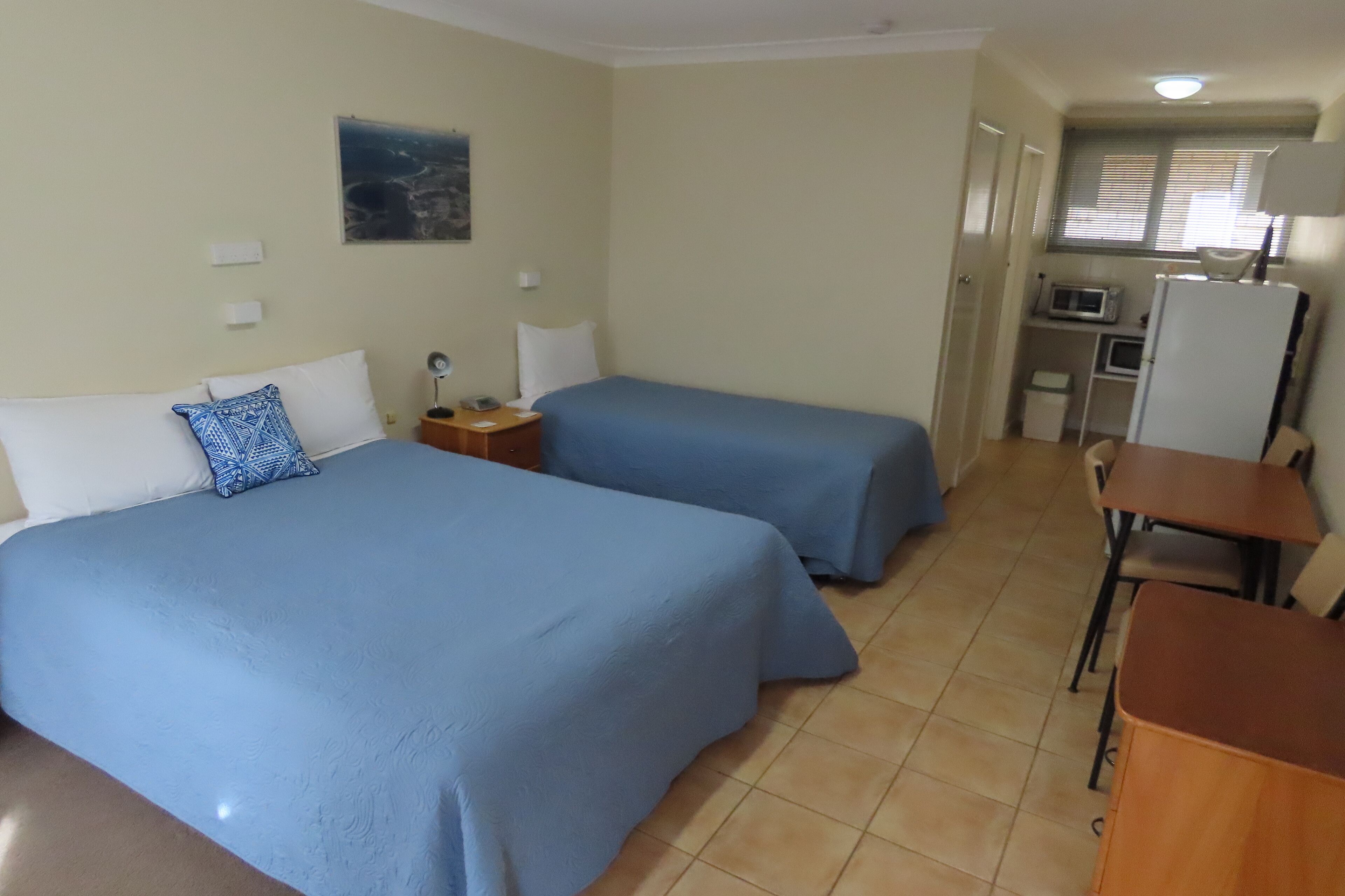 Habitación de hotel con dos camas, un escritorio, una silla, un microondas y un refrigerador.