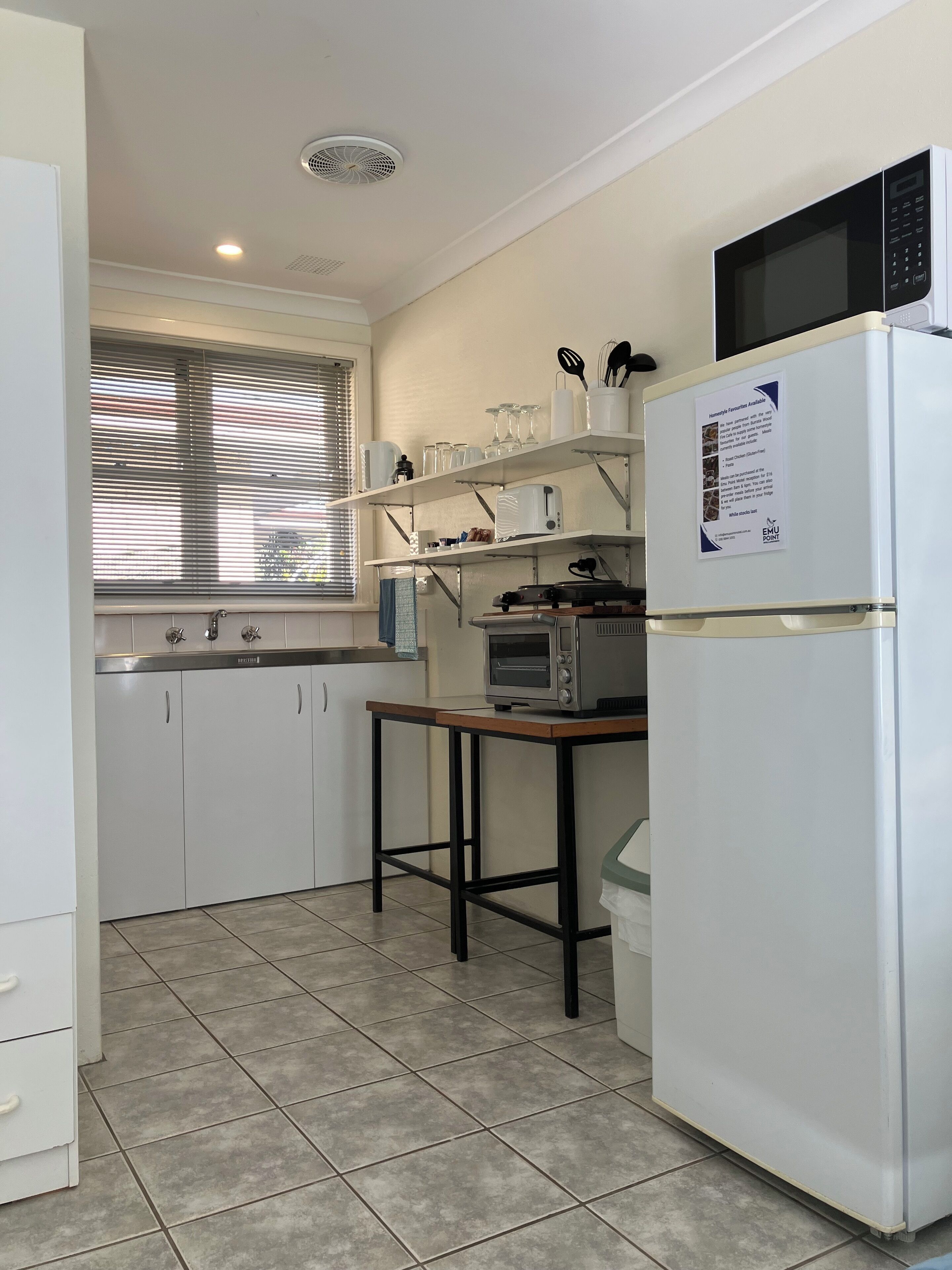 A compact kitchen with white cabinets, a microwave, a toaster, and a sink.