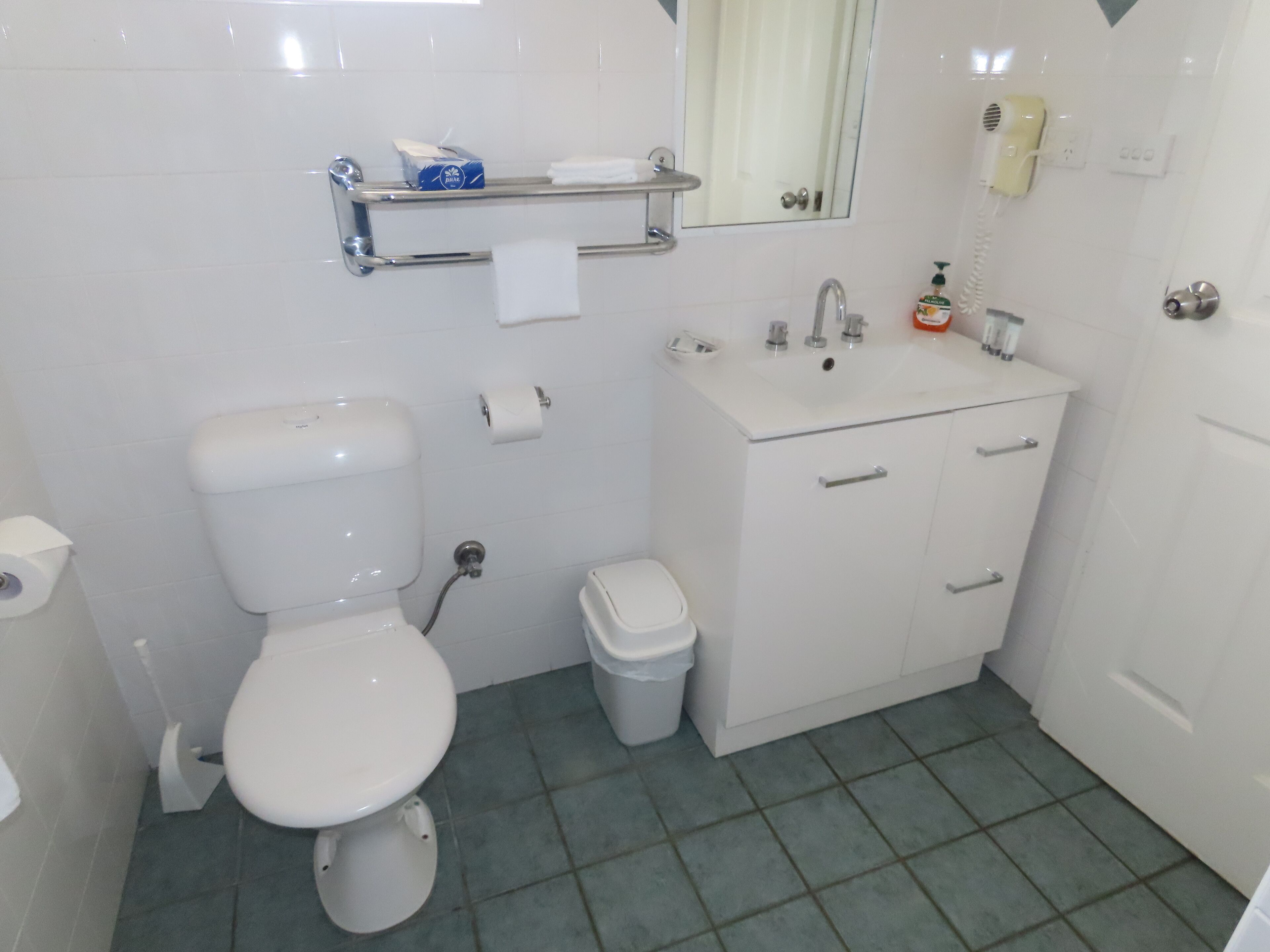 A bathroom with a toilet, sink, and mirror.