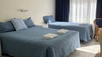 A hotel room with two beds, a window with curtains, a bedside table, and a chair.
