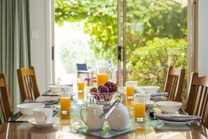 Una mesa de desayuno dispuesta con tazones, tazas, una jarrón y un frutero.