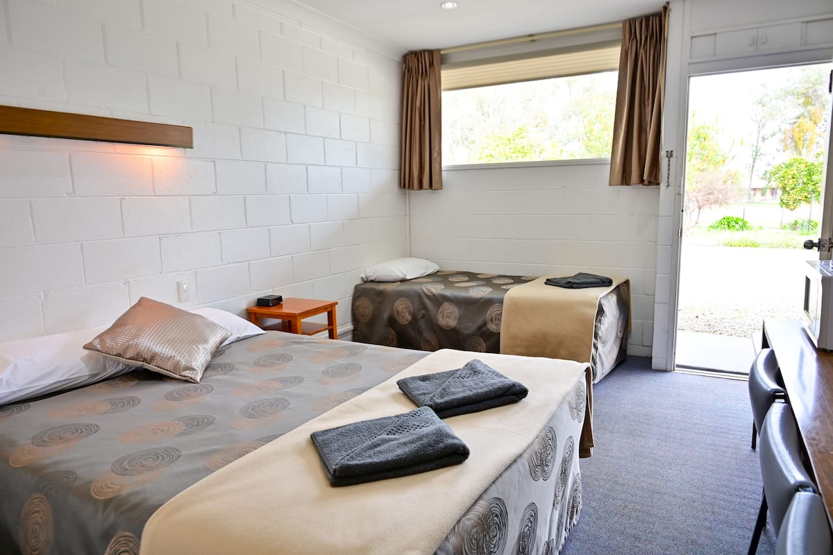 A room with two beds, a small table, and a bench.