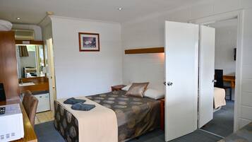 Un dormitorio pequeño con una cama, mesita de noche y un escritorio con computadora.