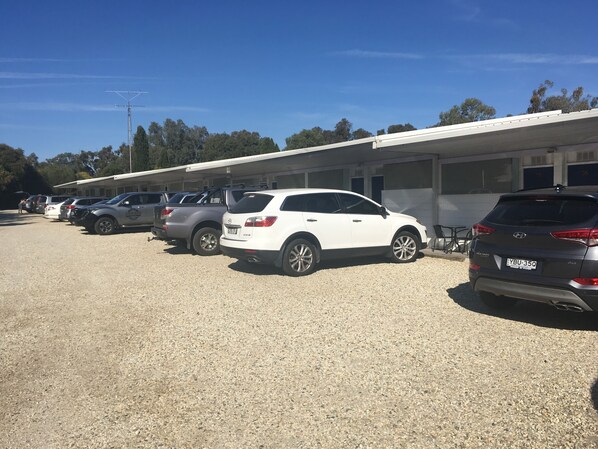 A parking lot with several cars parked in front of a building with multiple garage doors.