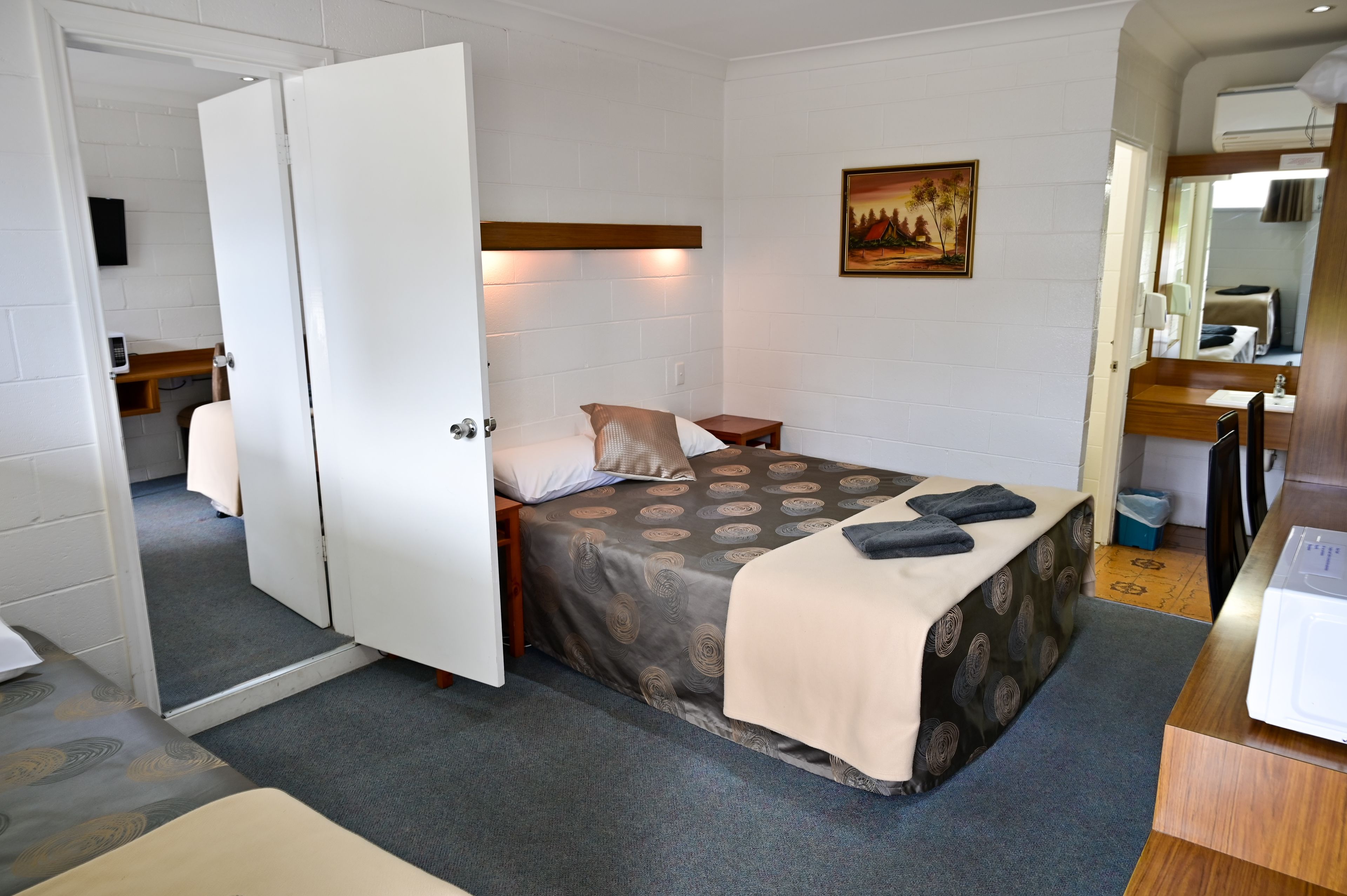 A bedroom with a bed, bedside table, and a painting on the wall.