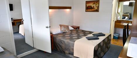A bedroom with a bed, bedside table, and a painting on the wall.