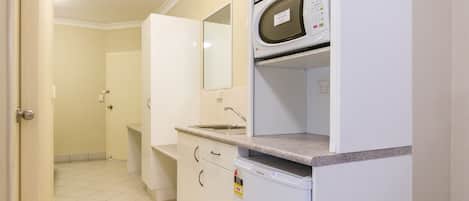 A kitchen with a microwave, sink, and cabinets.