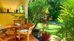 A patio with a wooden table, wicker chairs, and a potted plant. - Villa Marine Holiday Apartments (Yorkeys Knob)