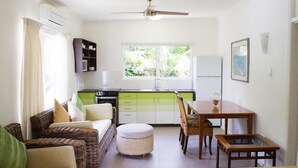 A compact living space with a kitchenette, a dining area, and a seating area with a sofa and ottoman. - Villa Marine Holiday Apartments (Yorkeys Knob)