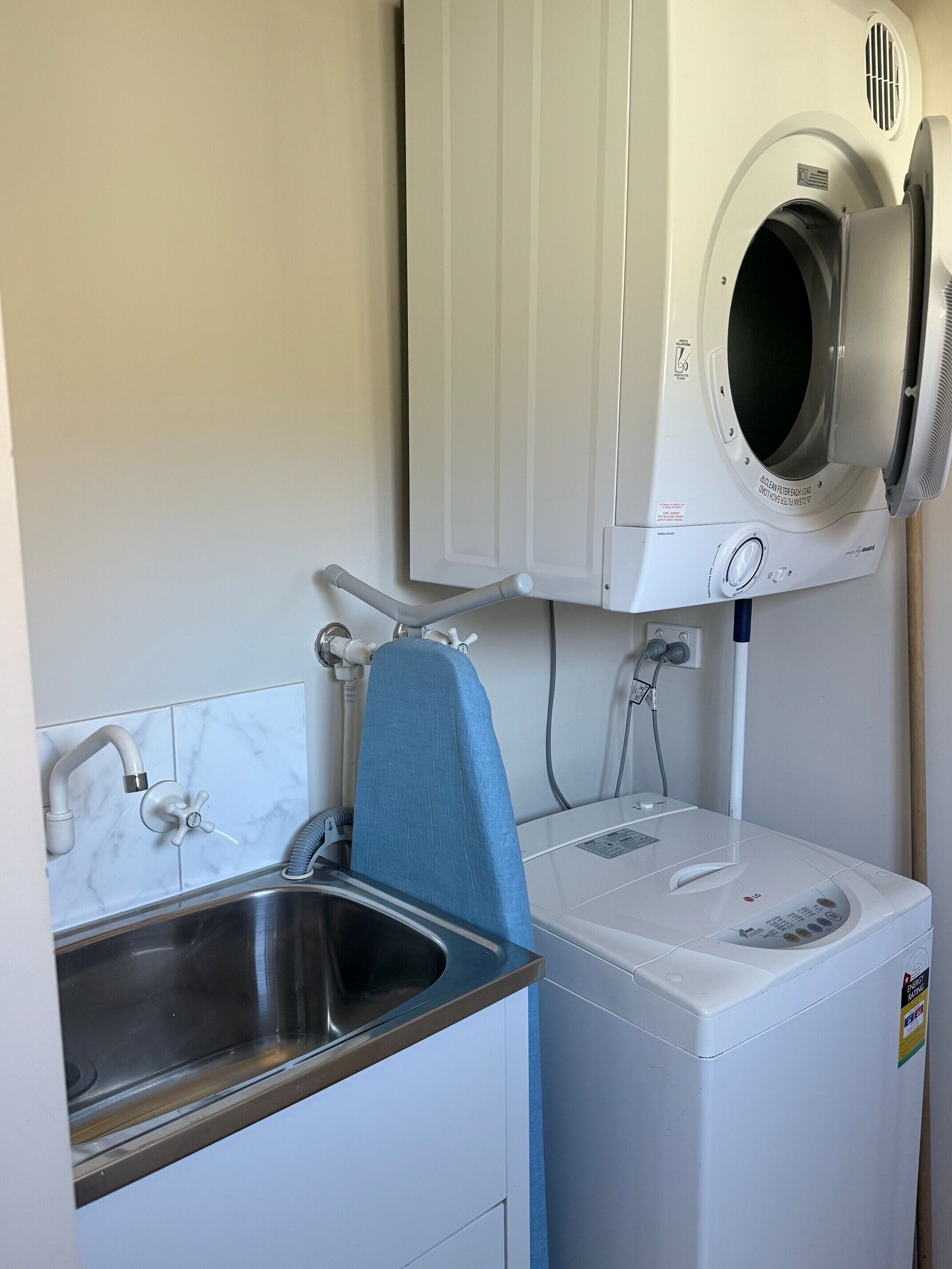 A compact laundry room with a washing machine, a dryer, and a sink.