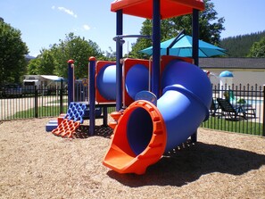A playground with a slide, climbing area, and a fenced play area.