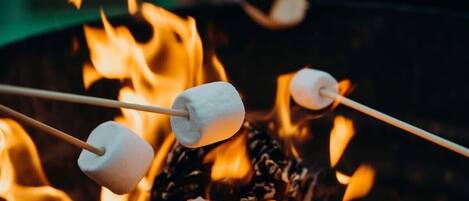 Fogueira com marshmallows espetados em gravetos.