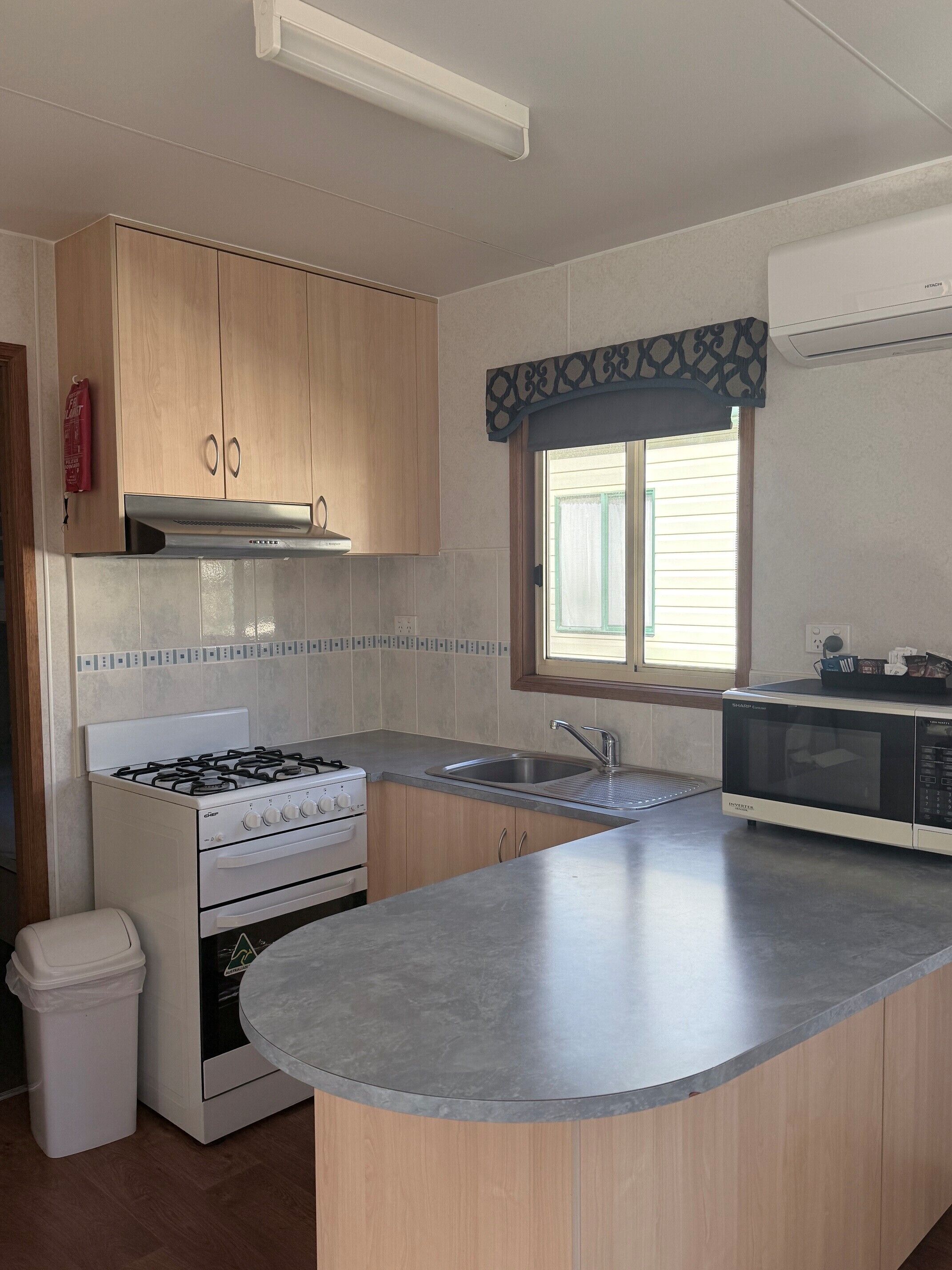 A kitchen with a gas stove, oven, microwave, and a sink.