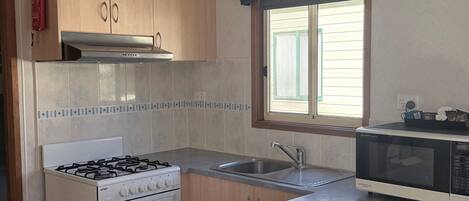 A kitchen with a gas stove, oven, microwave, and a sink.