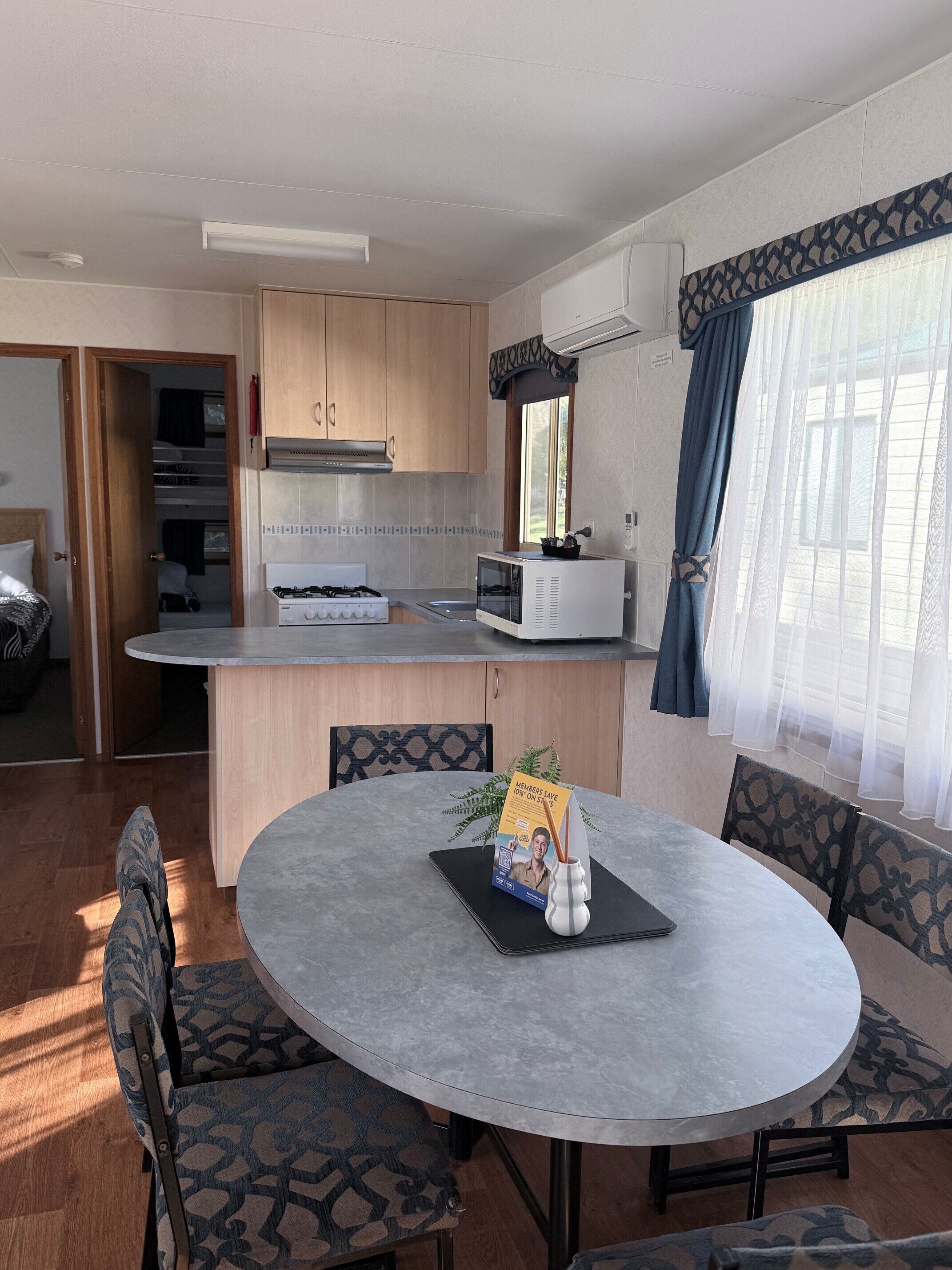 A compact kitchen with a dining area, including a round table and chairs, a microwave, and a gas stove.