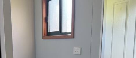 Een badkamer met toilet, toiletpapier, een plank met toiletartikelen, een spiegel en een wastafel.
