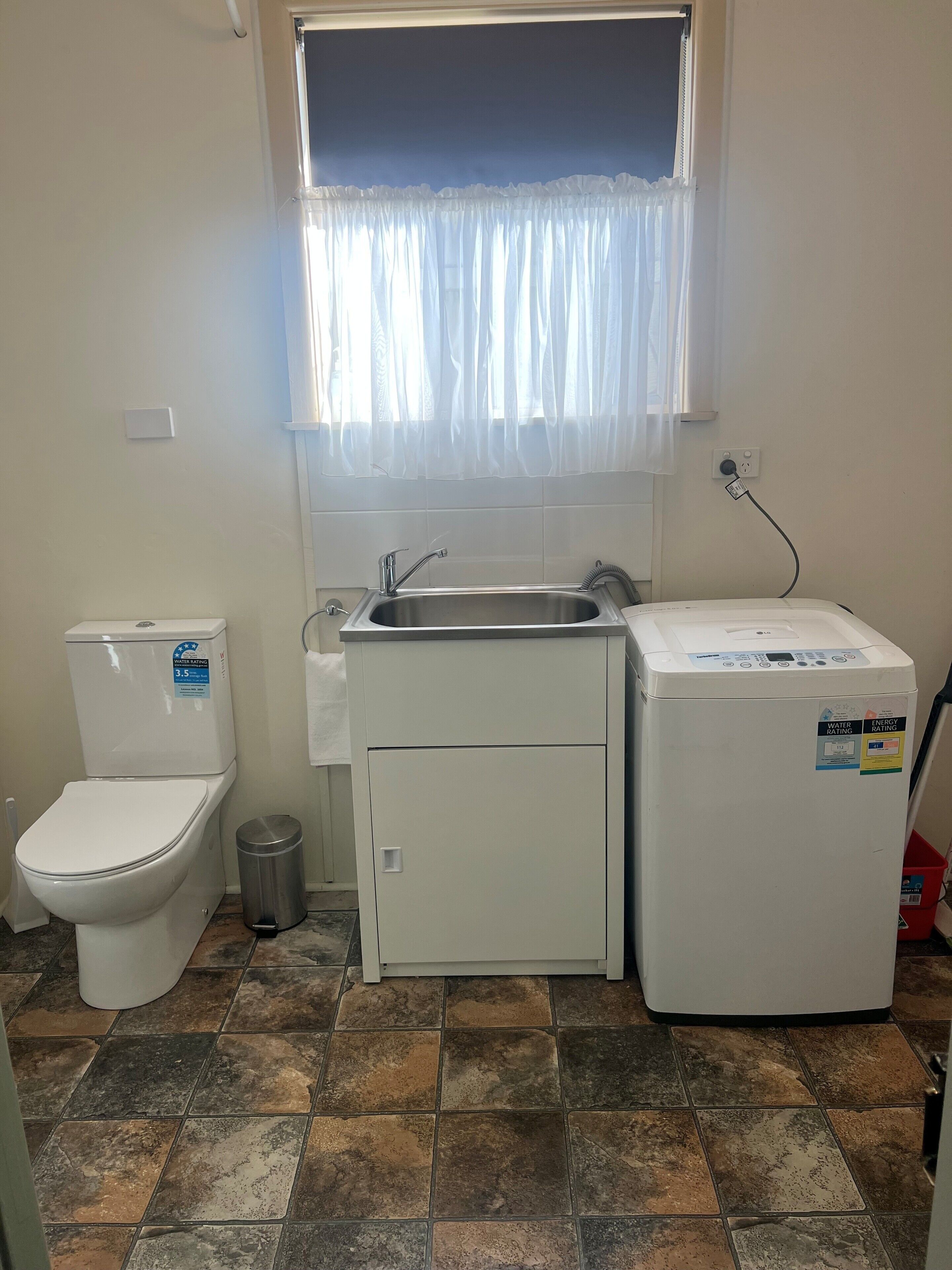 Ein kleines Badezimmer mit Toilette, Waschbecken und Waschmaschine.