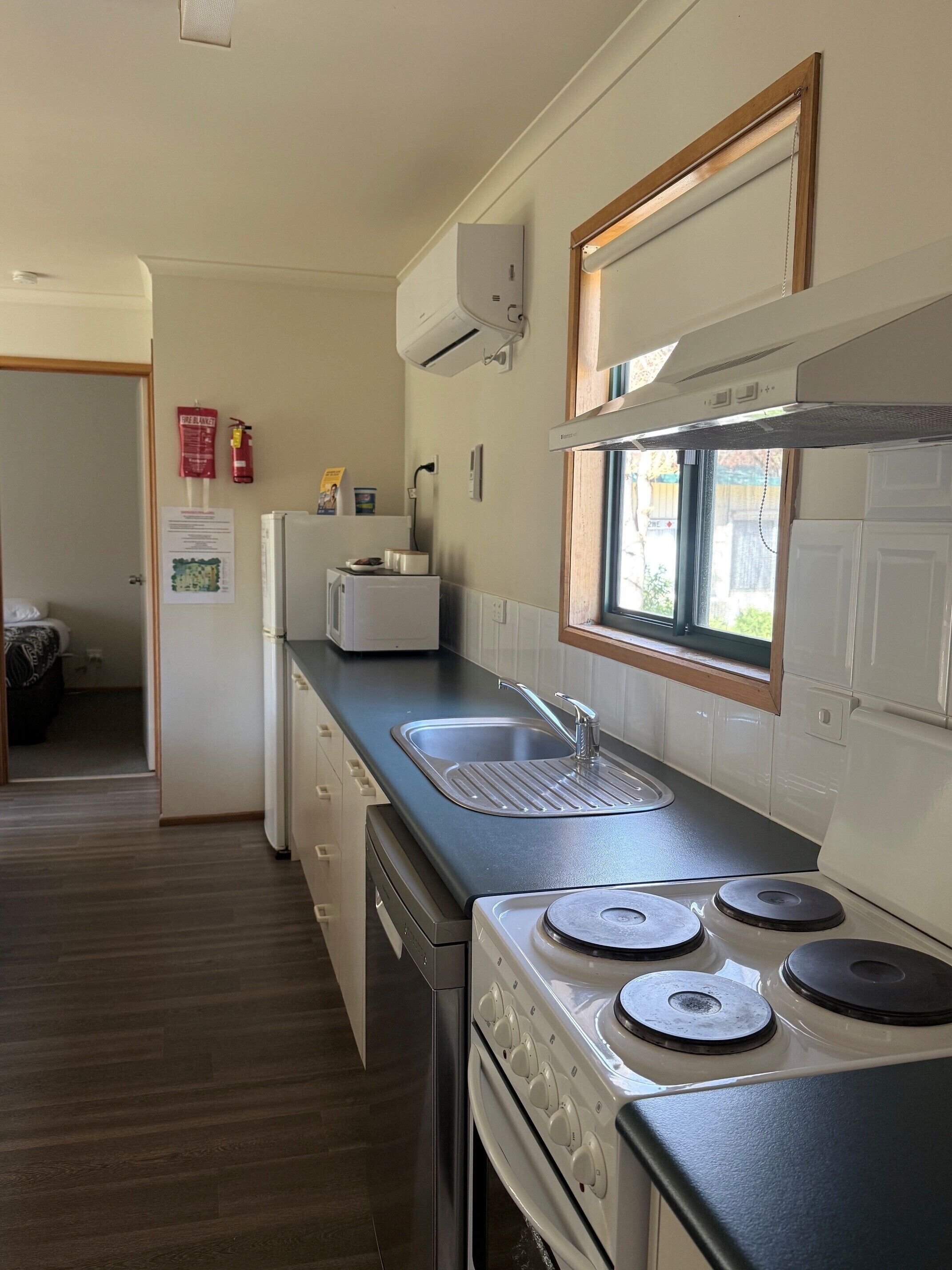 A compact kitchen with a built-in stove, a sink, and a window.