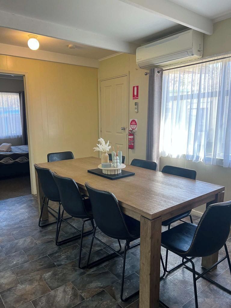 A dining area with a wooden table, black chairs, and a vase with white flowers.