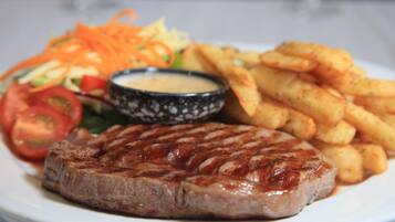 Ein Teller mit gegrilltem Steak, Pommes Frites, Salat und einer Soße.