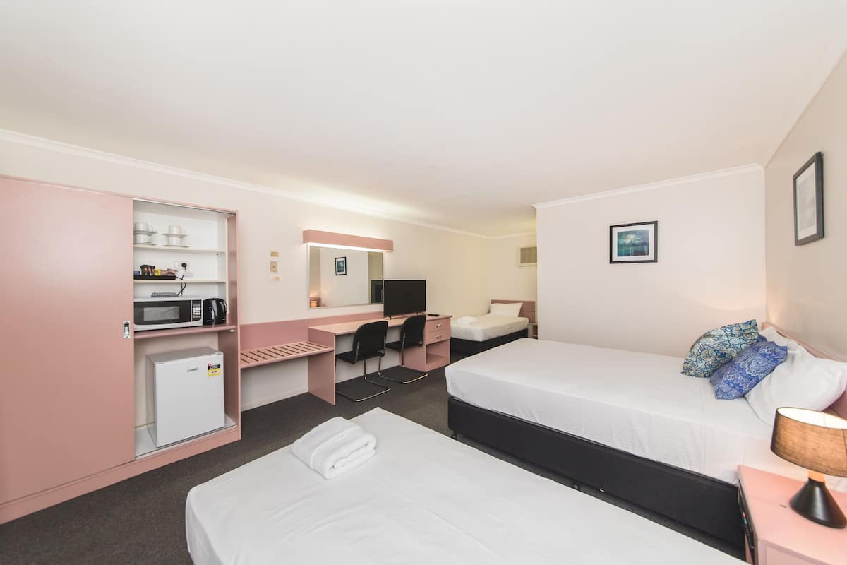 A hotel room with two beds, a desk, a microwave, and a small refrigerator.