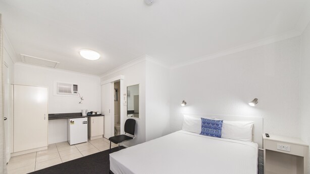 A hotel room with a bed, a desk, a chair, a wardrobe, and a nightstand. - Metro Motel Rockhampton (Rockhampton)