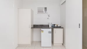 A compact kitchenette with a refrigerator, a microwave, and a coffee maker on the countertop. - Metro Motel Rockhampton (Rockhampton)