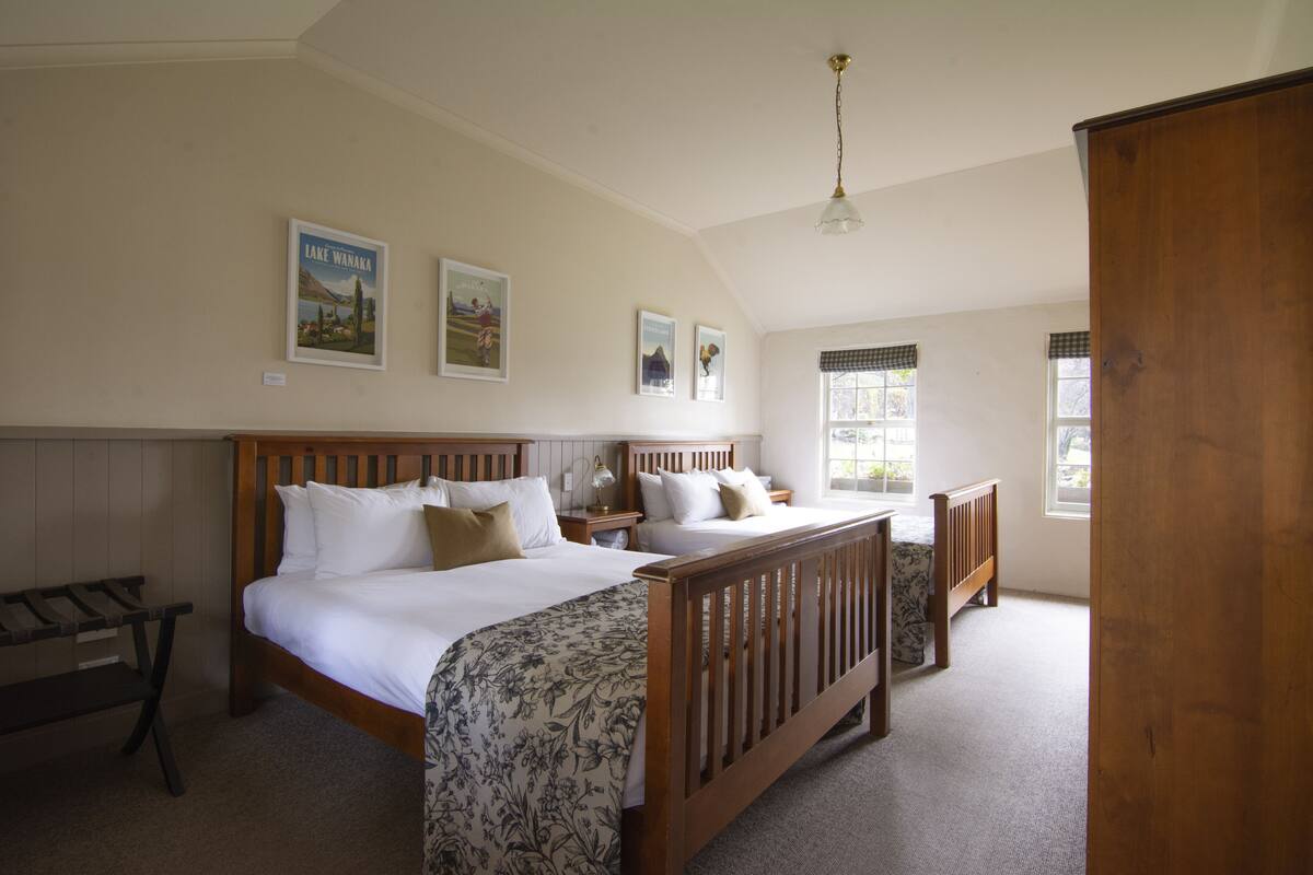 A bedroom with two single beds, a wooden bench, and a large wardrobe.