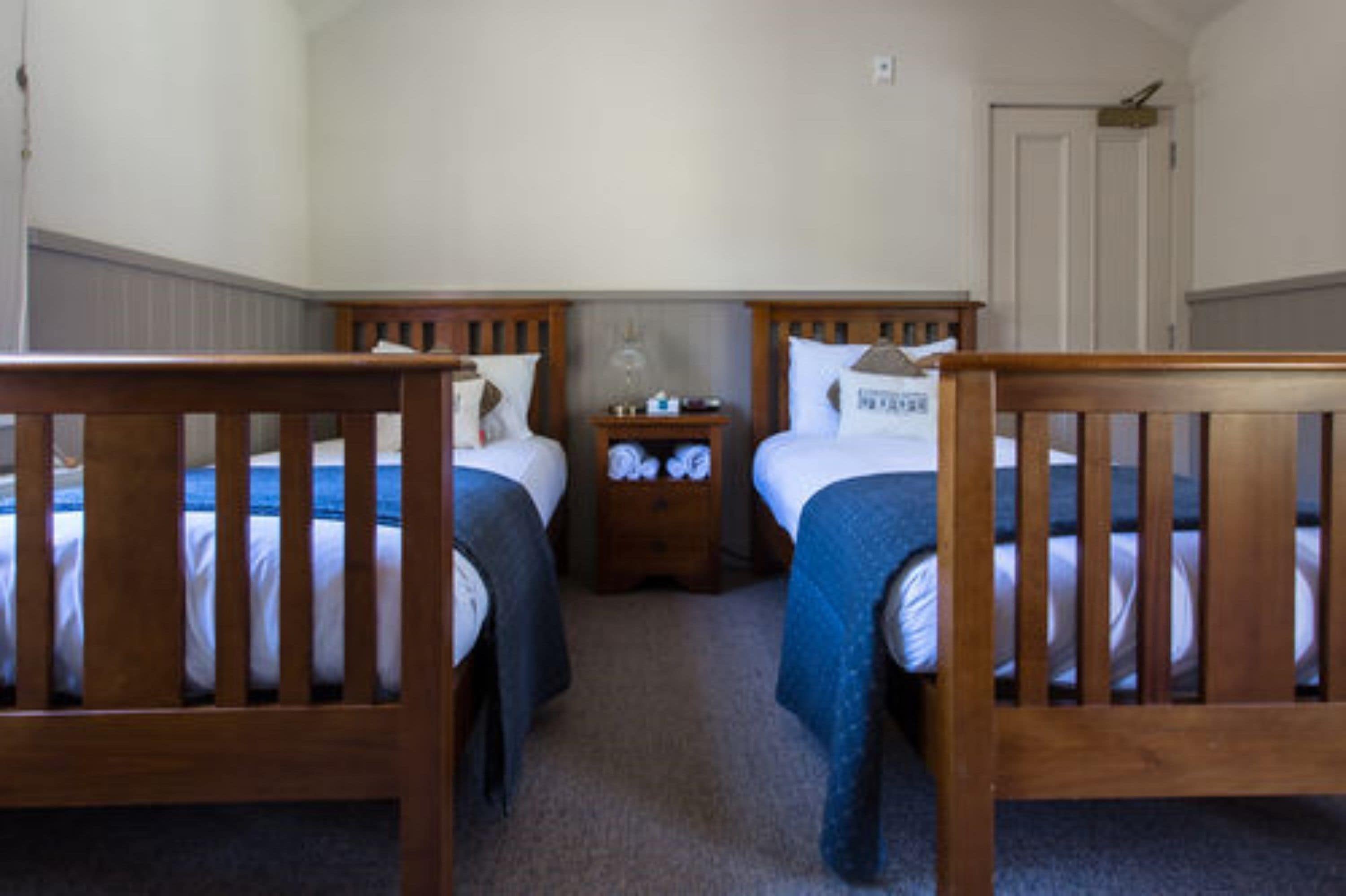 A room with two wooden beds, a nightstand, and a door.