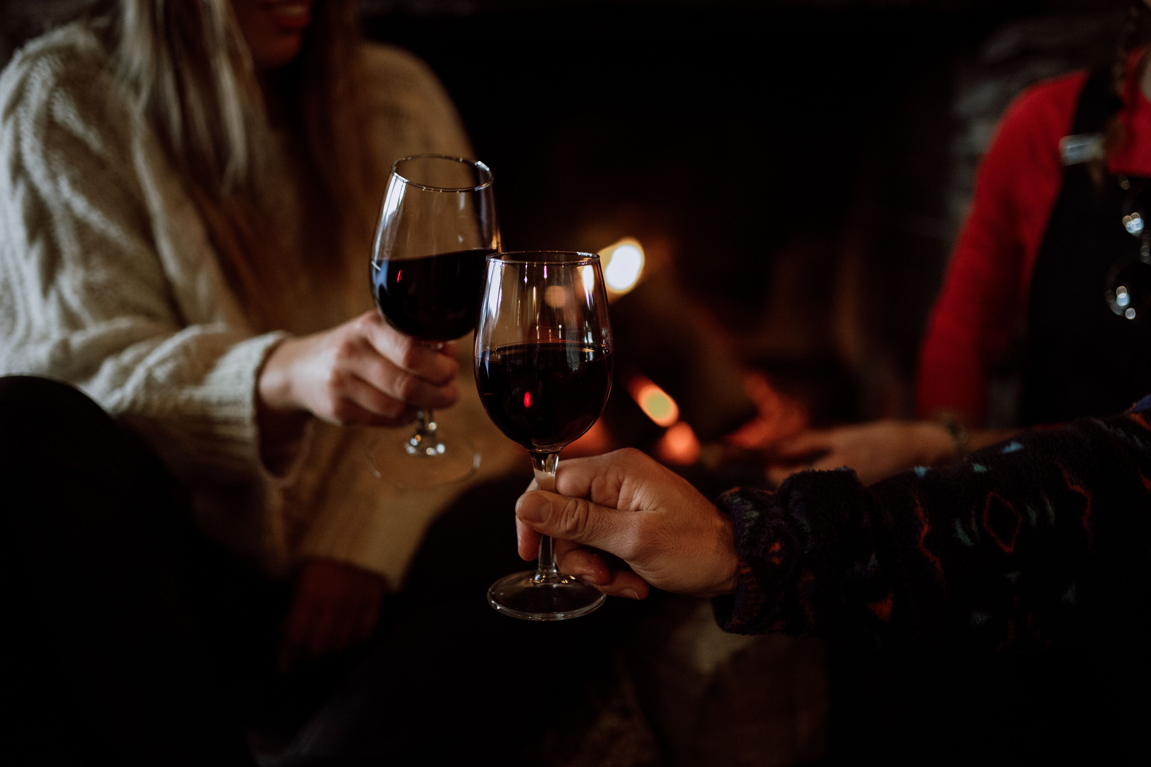 Due persone che sorseggiano vino in un ambiente scarsamente illuminato.