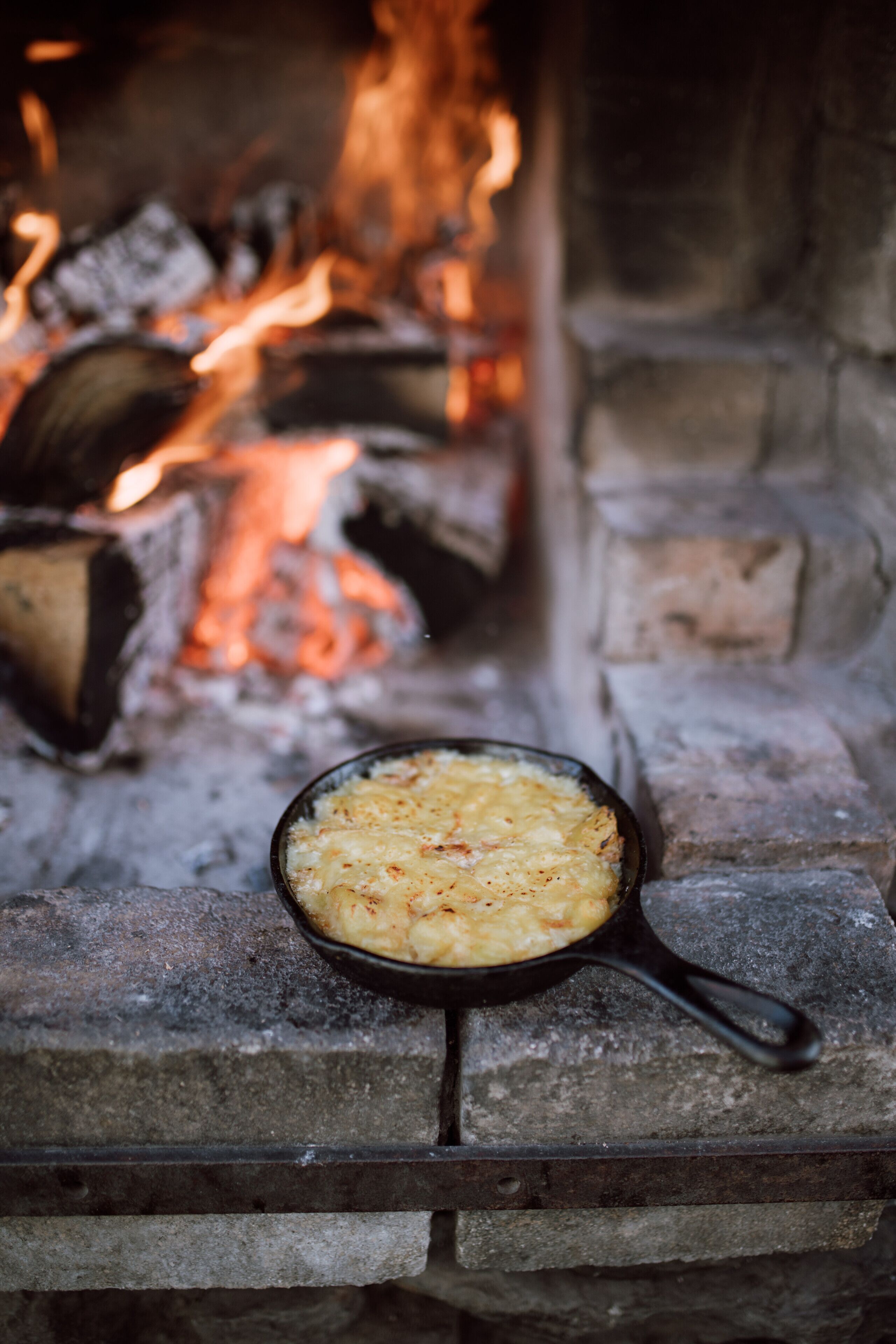 A cast iron skillet with a baked dish on a stone fireplace.